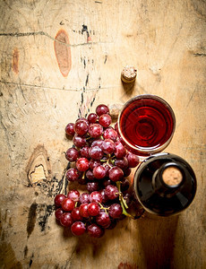 红葡萄和一瓶酒木制背景图片