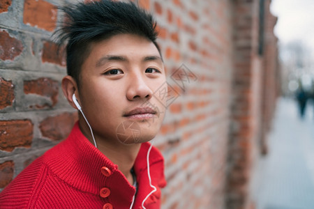 在街头城市概念中年轻小男孩在户外用耳机收听音乐的肖像图片