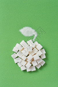 苹果实的创作成分来自不同种类的糖压立方块和叶子颗粒糖在浅绿色背景上复制空间平地糖块和叶子的手工苹果在绿色背景上图片