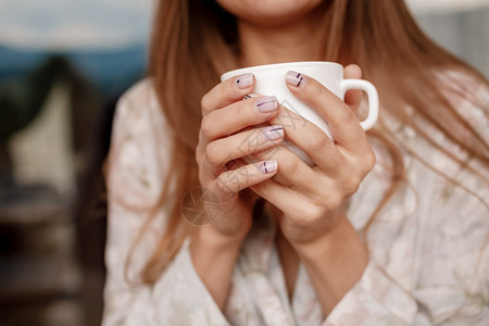 女孩握着白色杯子的手加上咖啡或茶女孩和握着白色杯子的手加上咖啡或茶图片