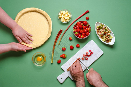 草莓和胡巴蛋糕在绿桌上以最顶层的视野制作图片
