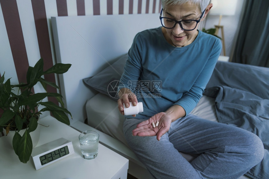 美拉通宁用于促进健康睡眠成年妇女在睡觉前服用美拉通宁补充药丸图片