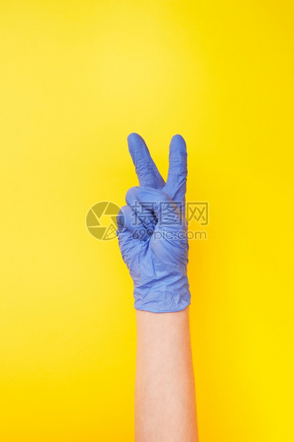 妇女手持紫色橡胶保护手套显示黄色背景的象征胜利复制空间防止细菌和的概念签名胜利让女手持橡胶保护套图片