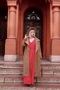 金发女郎穿着红色的礼服和帽子在城市里时装版的金发模特儿时装版的金色模特儿图片