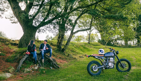 年轻夫妇在户外喝啤酒的摩托车旅行中休息图片