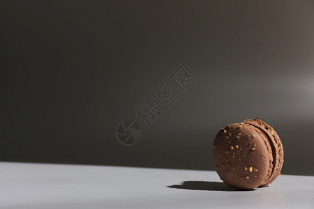 一份棕色巧克力面粉蛋糕或有窗外阴影的马卡龙蛋糕在白和灰背景上被孤立的美味马卡龙一份法国甜饼干一份白和灰背景上被孤立的美味马卡龙一图片