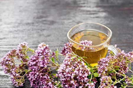 杯子里的香草茶木板底的鲜粉红花朵图片