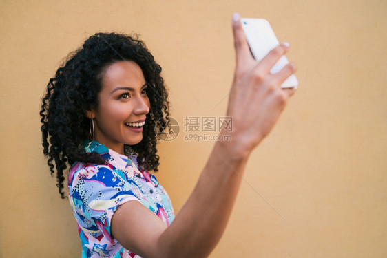 在黄色墙上拍自的for女人的肖像技术概念图片