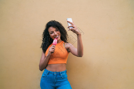 在吃冰淇淋时用手机自拍的for妇女肖像技术和生活方式概念图片