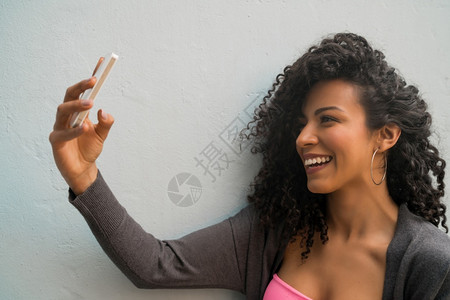 在灰墙上用手机自拍的for妇女肖像技术概念图片