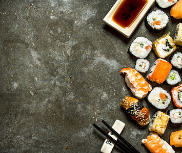 寿司卷和海鲜酱油放在石板上图片