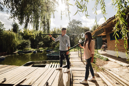 情侣在湖边木桥上拿着鱼竿图片