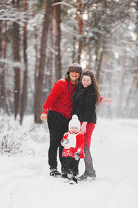 一个美丽的家庭在冬天雪林里玩得开心母亲父和小胖子穿着红衣在户外度日假期圣诞节幸福在一起爱的童年图片