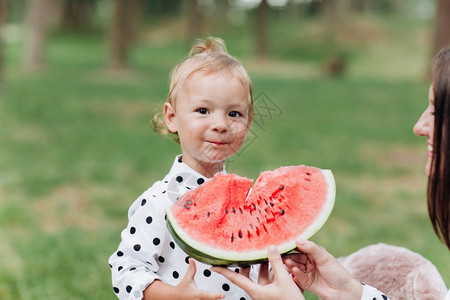 快乐的母亲和女儿在夏季公园吃西瓜快乐的笑脸家庭在公园吃西瓜母亲和女儿一起度过时间饮食维生素健康食品概念选择关注饮食健康品概念选择图片