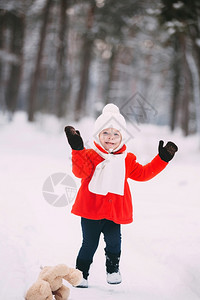 穿着红大衣的小女孩和一只泰迪熊在冬天玩得开心女孩在雪地玩耍女孩在冬天玩得开心图片