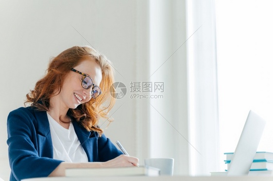 坐在内阁的笔记本电脑前微笑的导演记下财务报告的信息笔记本电脑的工作图片