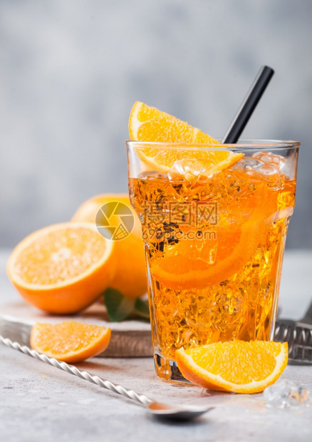 在高球杯中用橙子和勺来配上aperolsitz夏季鸡尾酒在浅色桌底背景上冰块和黑草图片