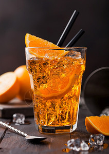 在高球杯中用橙片和勺子在黑底面上用冰块和配上高球杯的aperolsitz夏季鸡尾酒图片