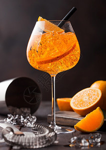 一杯橙色鸡尾酒和配有吉格鸡尾酒搅拌机的师木制背景和冰块图片
