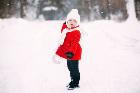 在冬季森林里穿着红大衣的漂亮小女孩冬天玩得开心的小女孩戴着手套和白帽子的快乐小女孩图片