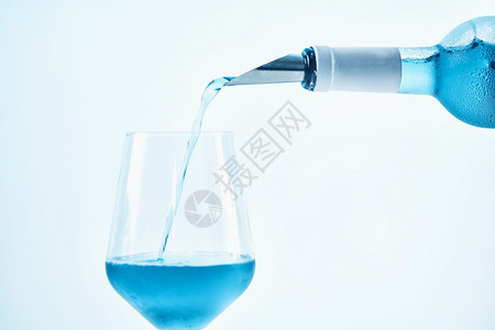 盛满蓝色葡萄酒喷出水泡和倒入葡萄酒杯中关上图片