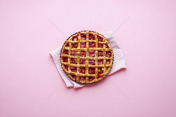 粉红色背景上方的自制粗露和草莓馅饼图片