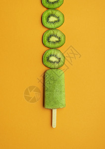绿色的棒棒糖椰子冰淇淋加片橙色背景绿冰淇淋棒热带夏季甜点新鲜食背景
