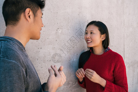 可爱的亚裔情侣肖像一边聊天看着对方图片