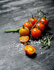 含盐和迷迭香的新鲜西红柿黑色生锈背景图片