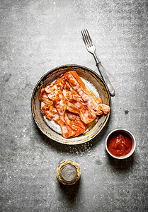 番茄酱和盐的炸培根石料背景的炸培根图片