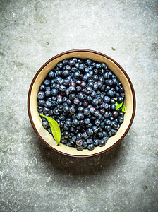 新鲜蓝莓放在杯子上石头桌图片