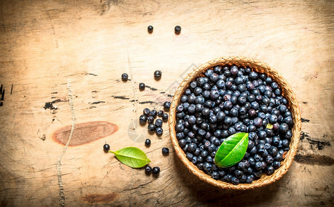 蓝莓在一个有叶子的杯里在木制桌上蓝莓在一个有叶子的杯里在木制桌子上图片