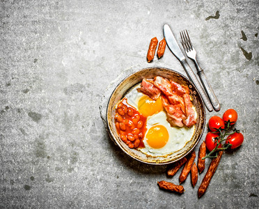 早上餐培根炸鸡蛋豆子和橙汁在石桌上图片