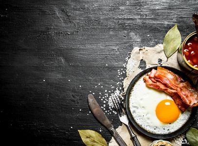 早餐豆酱加煎蛋和培根黑木背景图片