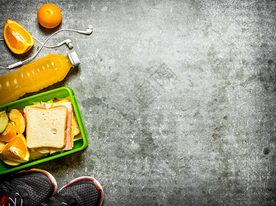 野餐三明治橙汁和水果在石桌上图片