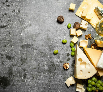 新鲜奶酪葡萄和白酒在石板上图片