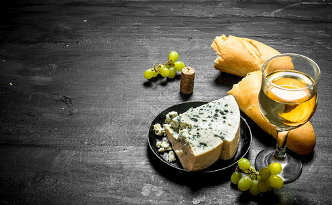 白葡萄酒蓝奶酪和西巴塔黑木本底图片