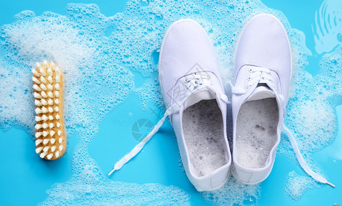 涂有粉末洗涤水溶解泡沫和蓝底的木刷洗脏鞋运动图片