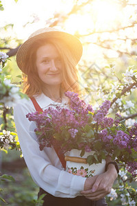 夏天穿着帽子和吊带的漂亮女孩在花园的里带一束图片