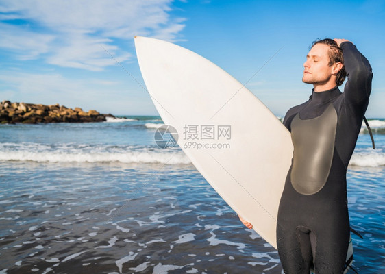 年青的冲浪者站在海洋中穿着黑色冲浪西装的板运动和水上的概念图片