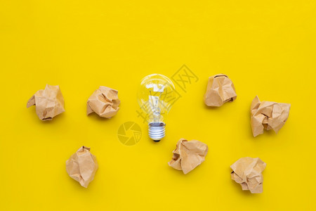 光面纸黄色背景的棕折面纸球灯泡顶部视图背景