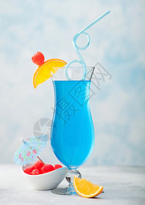 蓝色环礁夏季鸡尾酒经典玻璃甜鸡尾酒樱桃橙色切片蓝桌底的雨伞图片