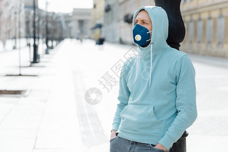 在户外拍摄的河马时穿着运动衫和呼吸面具在流行城市散步预防感染和冠状害怕感染图片