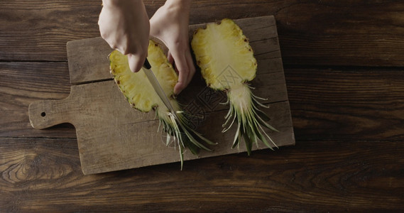 妇女手在切木板上的片开新鲜黄色天然热带菠萝的半径顶部视图运动频女和手在木制切片板上的一小节之中切开新鲜的黄色天然异质菠萝的半径顶图片