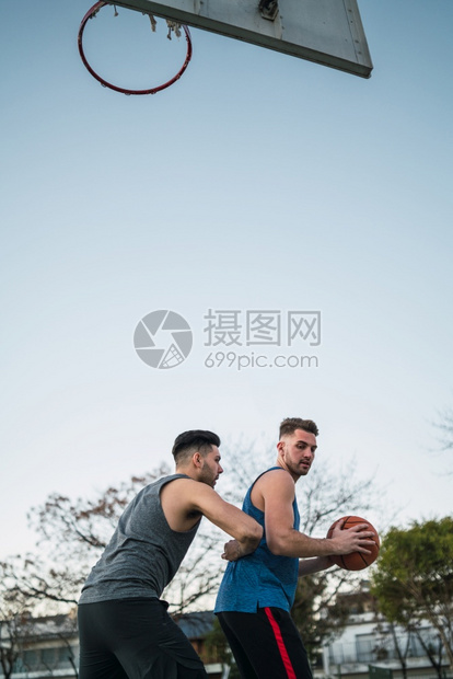 两个年轻朋友打篮球和在法庭户外玩乐的肖像体育概念图片
