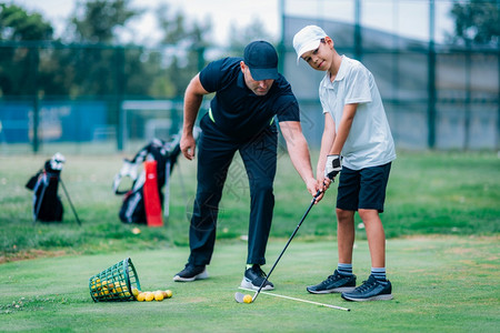 高尔夫球课教练和年轻男孩在高尔夫车场上高清图片