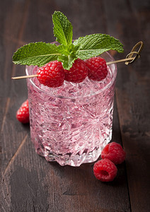 玻璃和冰的夏季粉红色柠檬鸡尾酒用草莓薄荷和生浆在木制背景上图片