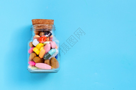 彩色药品丸片和玻璃胶囊蓝底复制空间图片