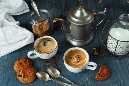 家庭早餐两杯咖啡加牛奶和自制燕麦饼干在蓝色木制旧餐桌上加巧克力土制风格低键图片