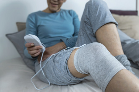 妇女在家里用导十电袜进行膝物理治疗图片